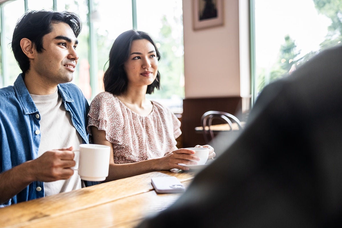 Friends having a casual conversation over coffee at café table