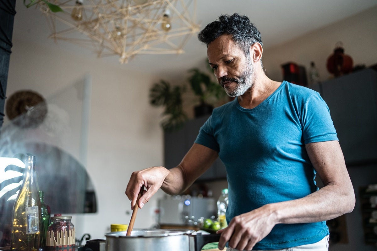Individual cooking at home in a modern kitchen, representing everyday life, household budgeting, and financial stability supported by smart personal banking solutions.