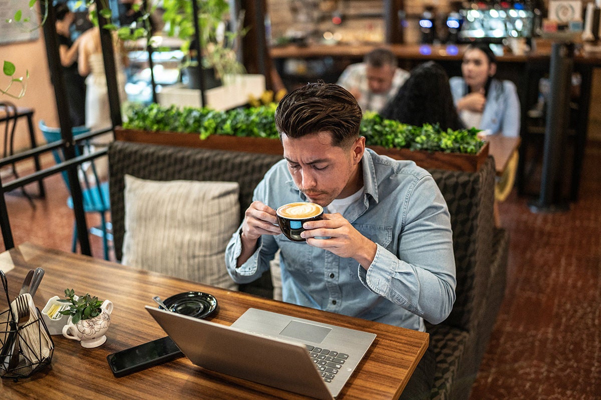 Mid adult businessman using laptop and drinking coffee in a restaurant