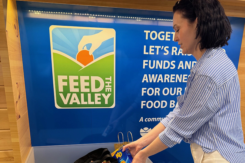 Employee adding food items to a Feed the Valley donation bin