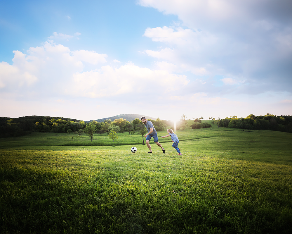 Father son duo playing football on the ground